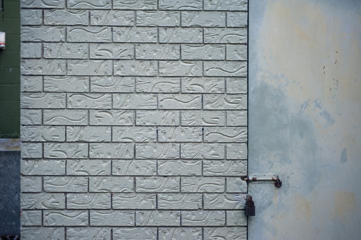 Architectural Detail of White Patterned Brick Wall and Closed Door Secured with Various Locks