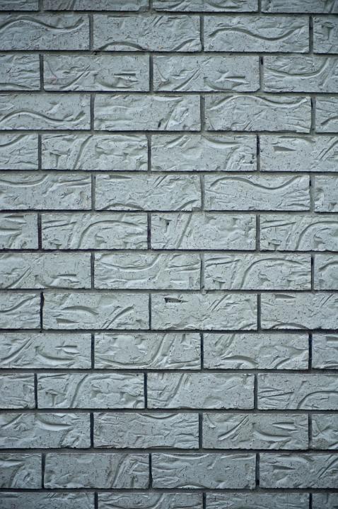 Textured Gray Brick Wall with Abstract Carvings for Background Designs, Emphasizing Copy Space.