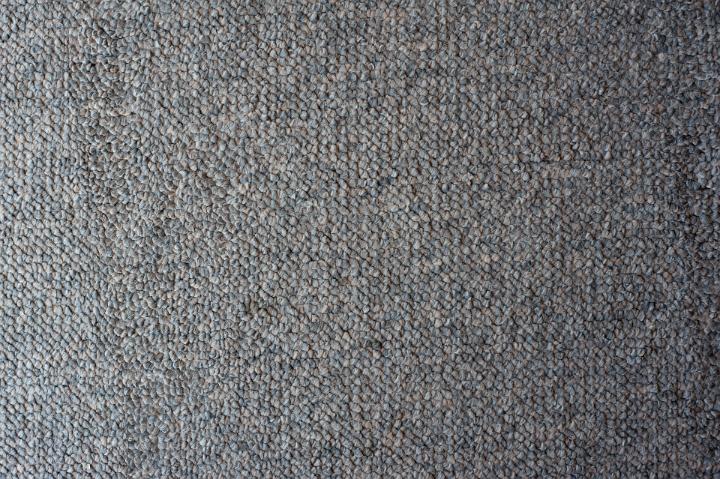 Carpet texture showing the weave of the fibers with no pile in a neutral beige, full frame textile background