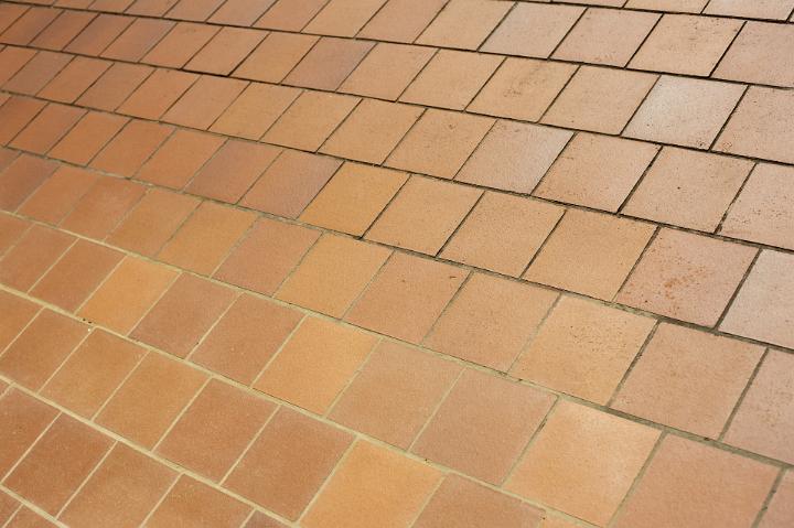 Oblique view of brown ceramic floor tiles in a receding perspective in a full frame architectural background