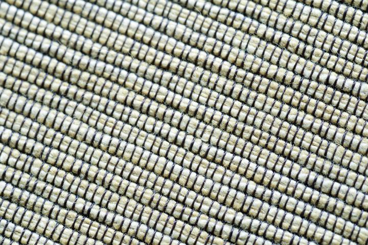 Full frame background texture of green corded fabric with the well defined stitching running in diagonal lines, close up overhead view