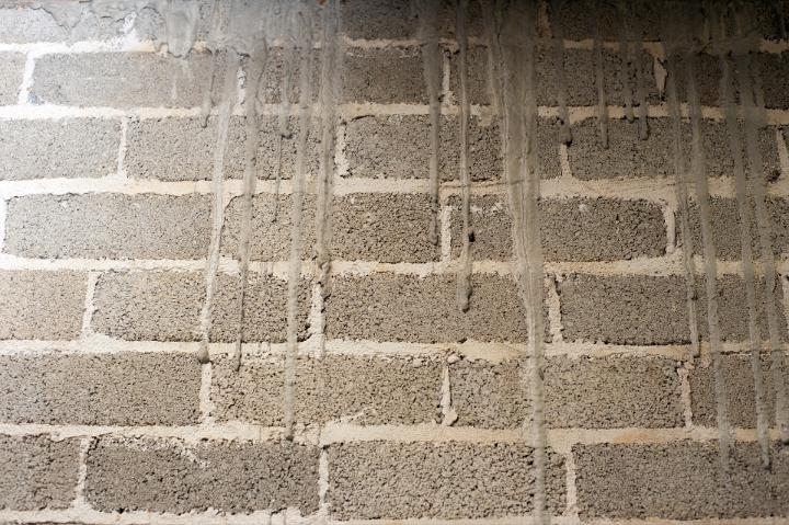 Irregular old wall made of gray grungy bricks and white mortar joint
