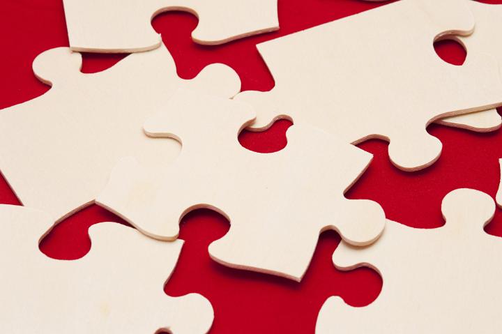 Close up Shot of Conceptual White Jigsaw Puzzle Pieces on Red Background