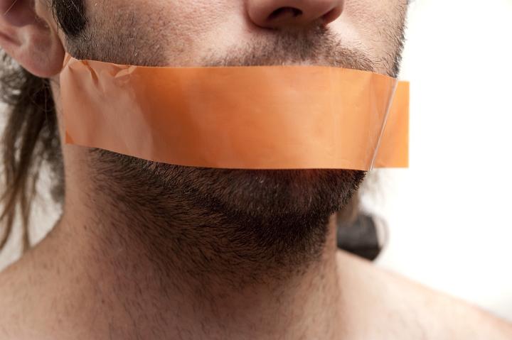 Close up Young Man with Beard and Mustache Putting a Brown Tape Over his Mouth for Silence Concept, Isolated on White Background.