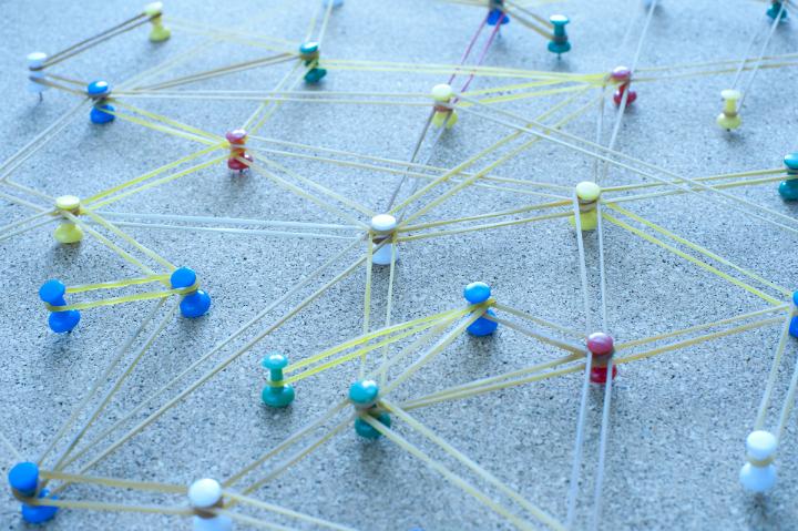 Network Concept Image Illustrated by Multi Colored Pins Inserted in Cork Board Connected by Elastic Rubber Bands