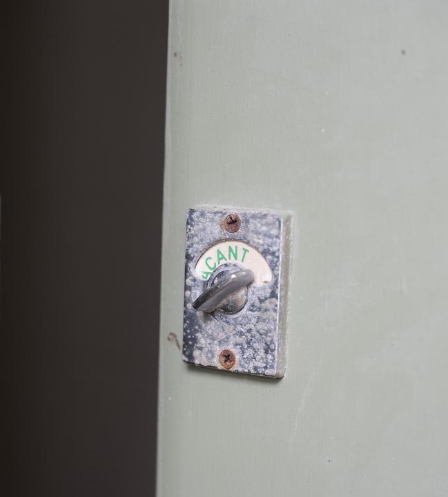 Vacant sign on the rotary lock of a white wooden restroom door allowing access to the facility