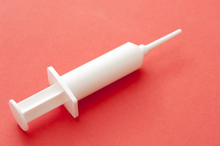Vaccination Concept - Close up White Plastic Syringe on Pink Background, Isolated on Pink Background, Emphasizing Copy Space.