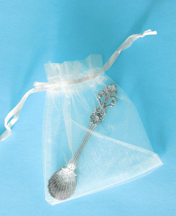 Christening gift for a baby boy with a decorative silver spoon wrapped in a see through drawstring gift bag viewed from above