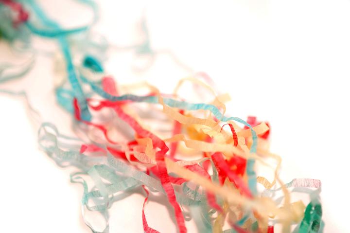Colorful tangle of festive party streamers arranged diagonally on a white background with copyspace for your greeting or invitation