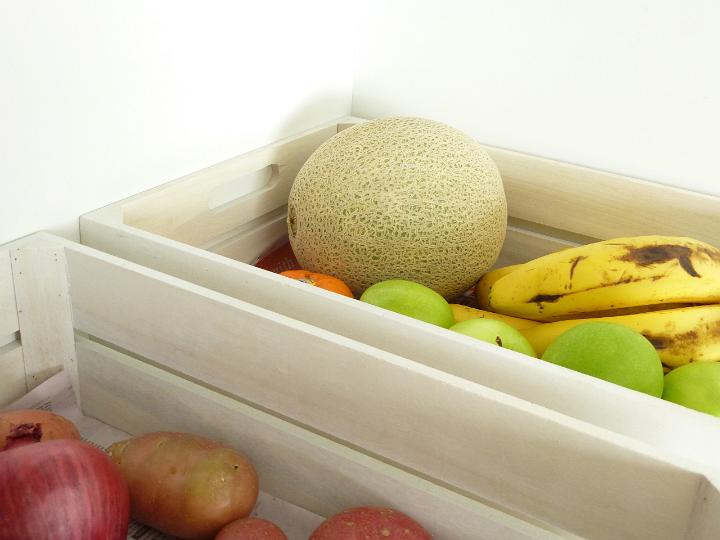Two wooden boxes of fresh fruit and vegetables including, bananas, apples, rock melon, onion and potato isolated on a plain white background.