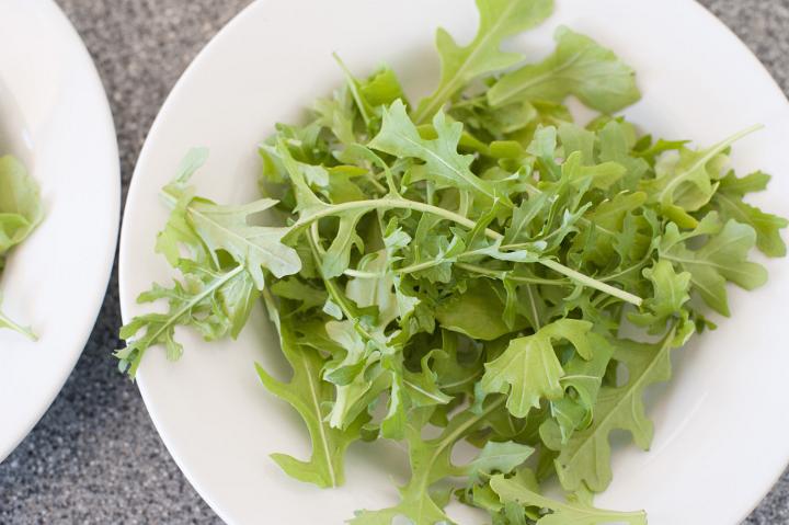 Above View of Leaves of Rocket Lettuce or Arugula in White Bowl on Counter Top