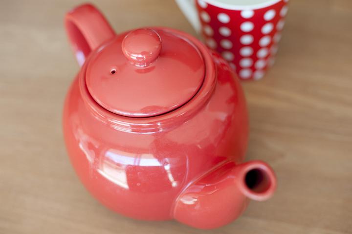 Close up Small Red Glossy Round Teapot on Top of Wooden Table