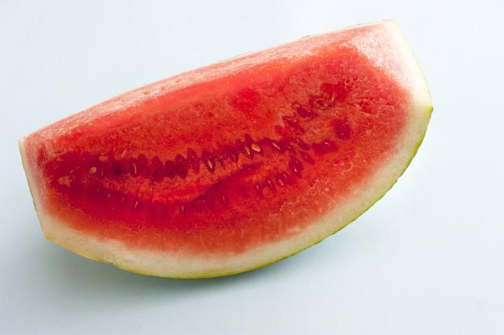 Tasty fresh slice of juicy watermelon for a healthy summer treat over a light grey background viewed close up
