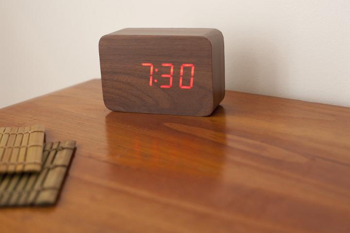 Alarm clock showing half past seven on a wooden table with copyspace