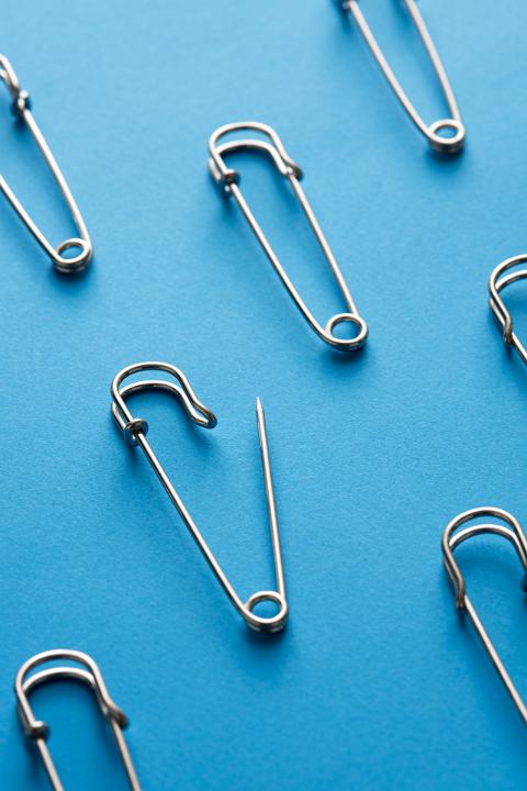 Close-up of safety pins arranged against blue background