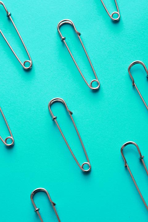 Closed safety pins arranged on blue background