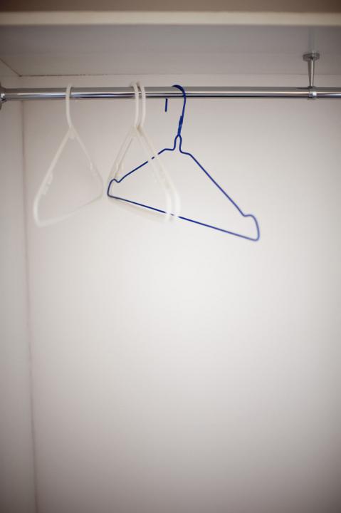 Empty wire coat hangers hanging on a metal rail in a closet or wardrobe with vignetting