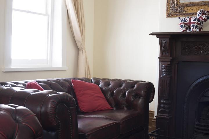 Large comfortable leather Chesterfield style armchair in a cozy study or living room standing in front of a bright window