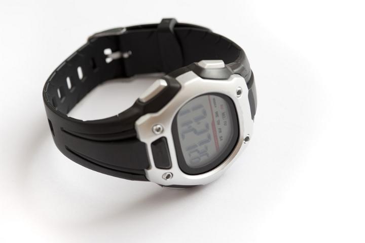 Mans wrist watch with a silver stainless steel surround and black strap with the display and time showing on a white background