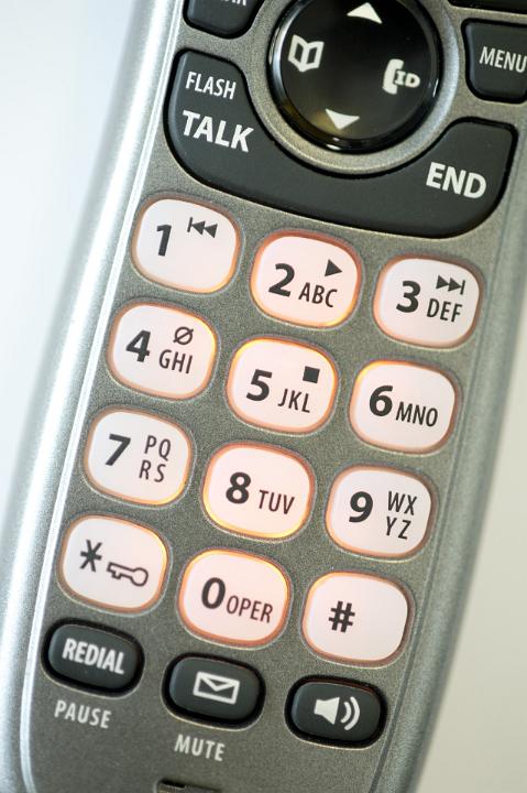 Close up overhead view of the keypad and keys with their numbers and alphabet letters on a telephone handset in a telecommunications concept