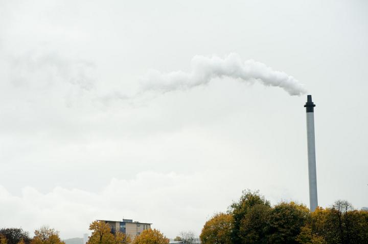 Industrial chimney belching smoke as it exhausts fumes and pollutants into the atmosphere at a refinery or plant, with copyspace