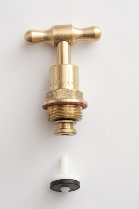 Close up detail of the internal parts in a brass garden tap, including a washer, isolated on a white background with copy space.