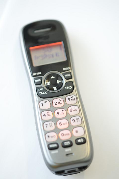 Wireless telephone handset lying on a white background in a telecommunications concept, high angle view