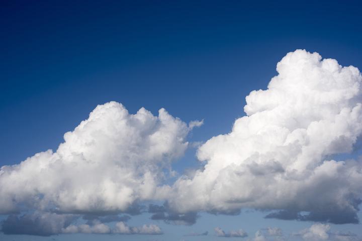 Beautiful fluffy white cumulonimbus clouds drifting in a vibrant clear blue sky.