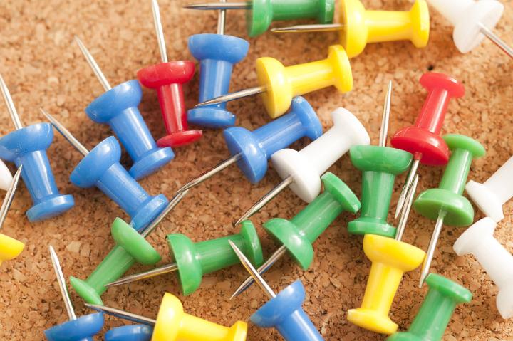 Close up Colorful Sharp Marker Pins on Top of Brown Cork Board