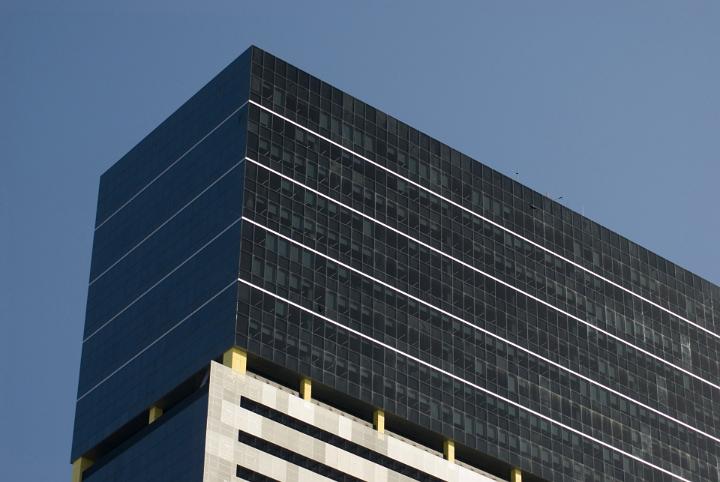 Top Part of Architectural Large Office Building with Glass Walls on Blue Gray Sky Background.