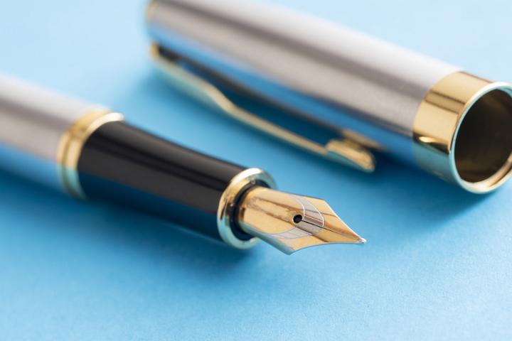 Close-up of pen with nib and cap on blue background