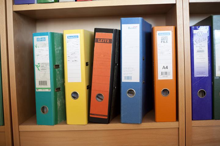 Close up Assorted Colored Ring Binders of File on Wooden Cabinet at the Office.