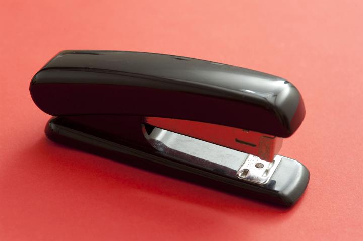 Close up Office Black Stapler Isolated on Red Background, Emphasizing Copy Space.