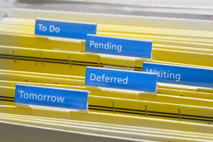 Close up Yellow Folders with Blue Labels for Work Procrastination Concept, Emphasizing To Do, Pending, Waiting, Deferred and Tomorrow Keywords.