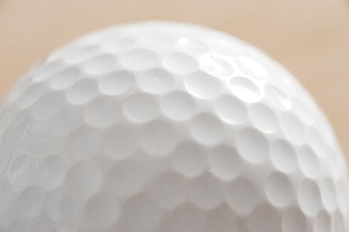 Close up detail of a white golf ball showing the dimpled texture of the surface in a golfing or sporting concept