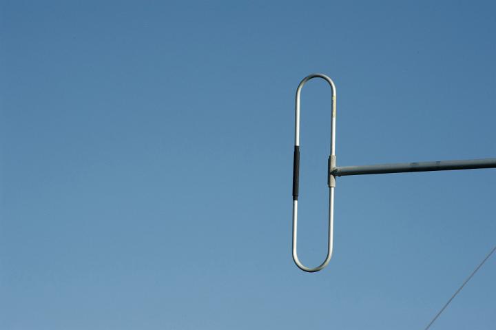 Dipole aerial metallic antenna used in radio and telecommunications, against a clear blue sky