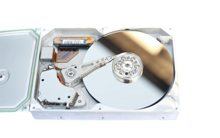 Detail of Open Hard Disk Drive Displaying Shiny Components, Open Case on White Background