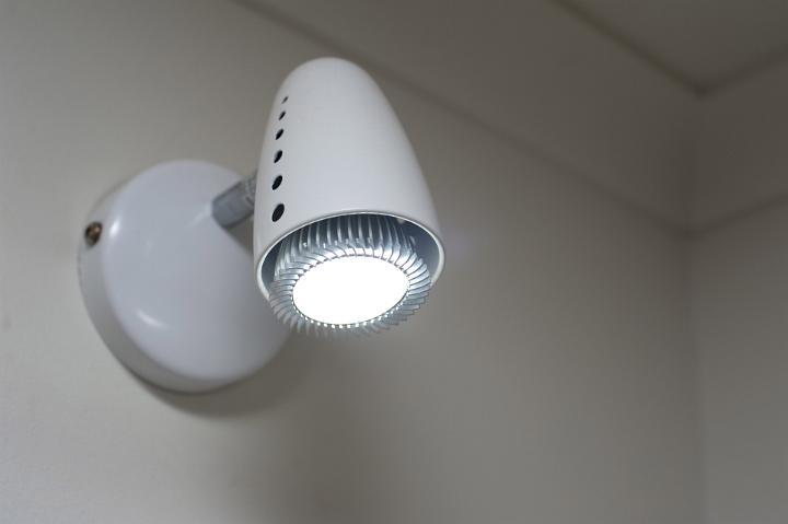 Illuminated LED wash light in a bathroom mounted on the wall shining downwards in the shadows in a close up view with copy space