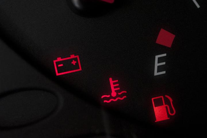 Illuminated red warning lights on a car dashboard during the ignition check showing the battery, temperature and fuel light