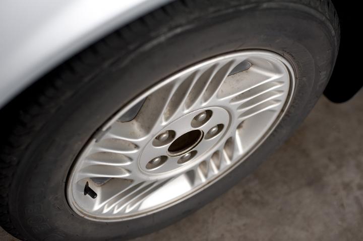 Wheel of a modern car tyre with a metallic ally sports rim viewed high angle parked on tarmac