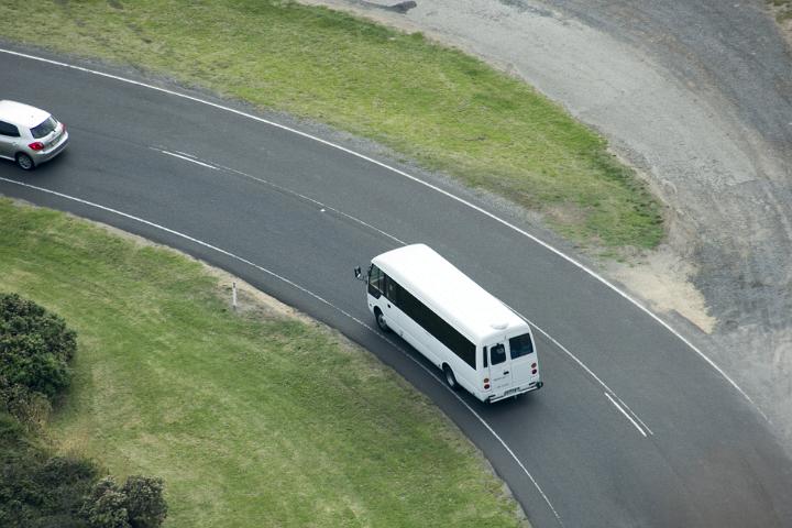 Aerial view of mini bus going along winding asphalt road