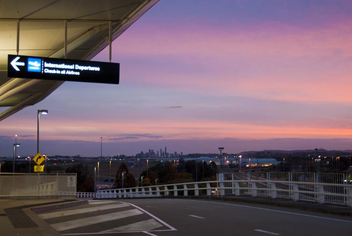 Drop off point outside an airport terminal with a view across the city at sunset with a colorful purple lilac sky