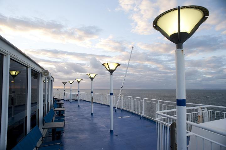 Deserted deck of a ferry in the evening with glowing lamps cruising mid ocean
