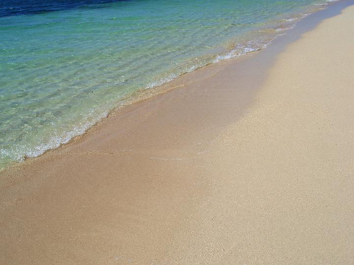 Clear blue sea lapping gently on a sandy beach in an idyllic tropical island background symbolic of summer vacations and travel